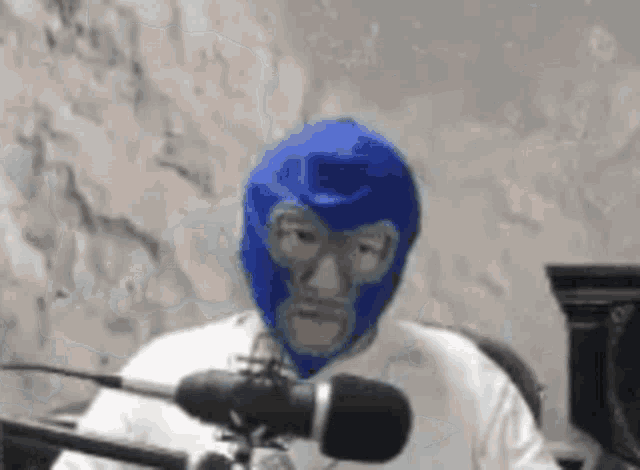 a man wearing a blue mask is sitting in front of a microphone