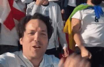 a man is standing in front of a crowd of people and making a funny face .