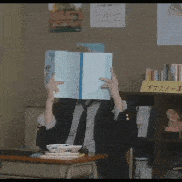 a person covering their face with a book in front of a sign that says ' osusume '