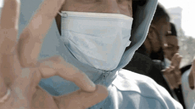 a person wearing a face mask is making a hand gesture