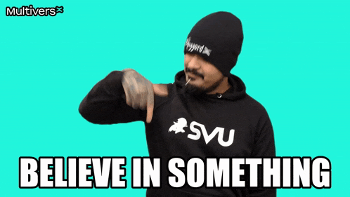 a man with a beard wearing a svu hoodie says " believe in something "