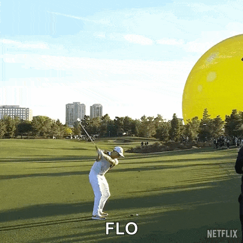 a man is swinging a golf club on a golf course and the word flo is visible