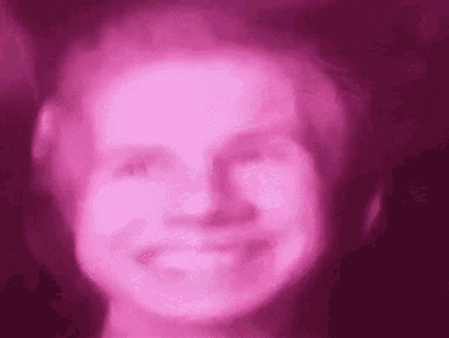 a close up of a person 's face with a pink light shining on it .