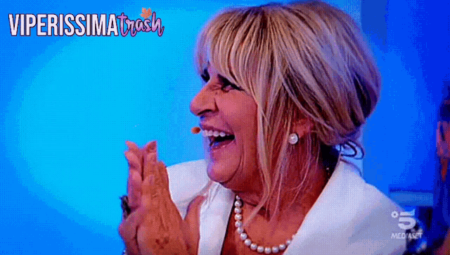 a woman is laughing in front of a blue background with viperissima trash written on the bottom