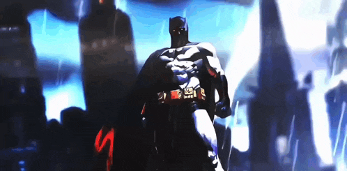 a man in a batman costume is standing in front of a crowd in a dark room .