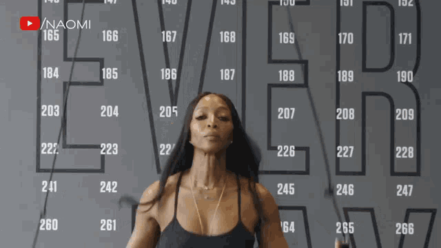 a woman is jumping a jump rope in front of a wall that says ever on it