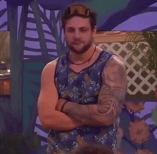 a man with a tattoo on his arm is standing with his arms crossed in front of a purple wall .