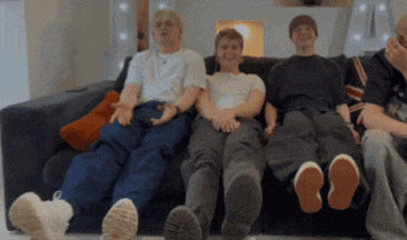 a group of young men are sitting on a couch with their legs crossed