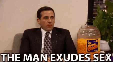 a man in a suit and tie sits in front of a jar of cheese balls and says the man exudes sex