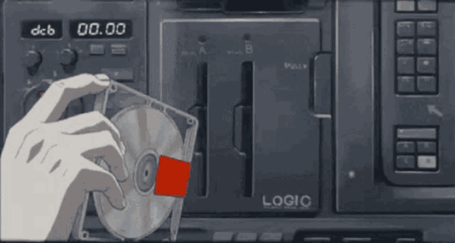 a hand holding a cd in front of a logic device