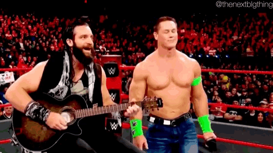 a man playing a guitar next to a shirtless wrestler in a wrestling ring