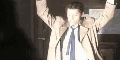 a man in a suit and tie is dancing with his arms in the air .
