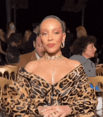 a woman in a leopard print jacket is sitting in a crowd of people at a party .