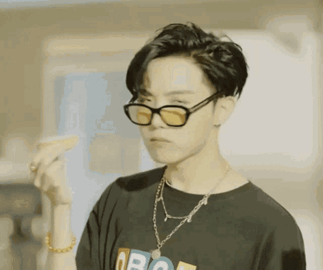a young man wearing sunglasses and a necklace is holding a piece of food in his hand .