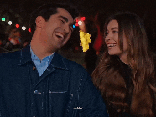 a man and a woman are laughing together and the man is wearing a denim jacket with the word arcadian on the collar
