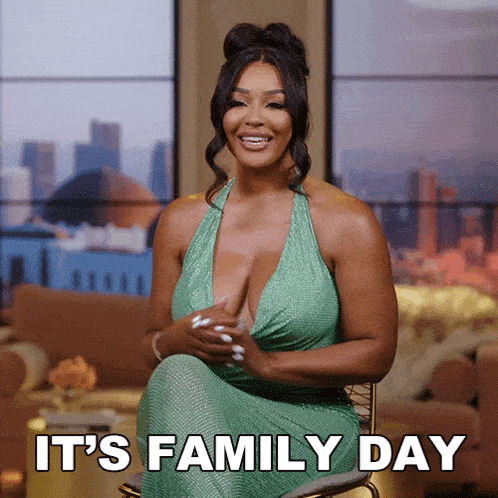 a woman in a green dress sits in a chair with the words " it 's family day " on the bottom