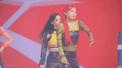 a group of women are dancing on a stage in front of a red background .