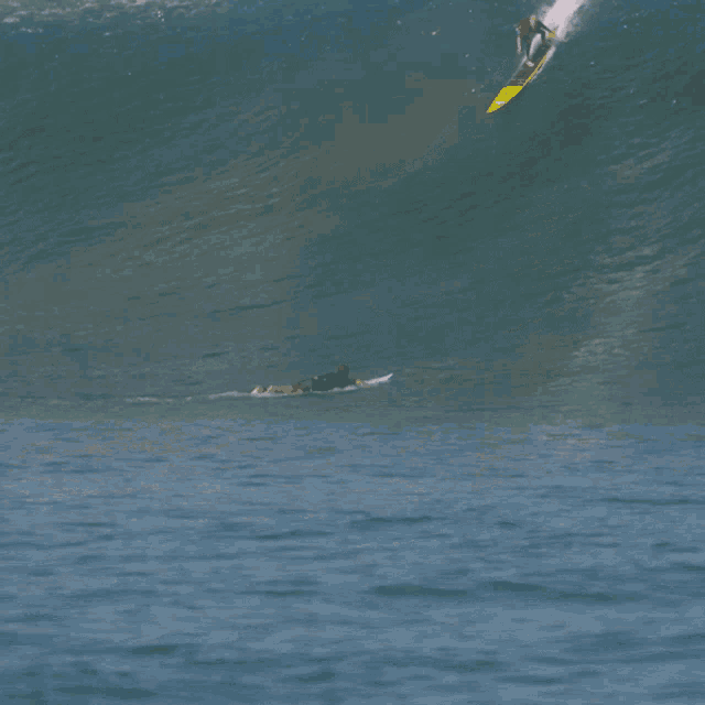 a surfer is riding a wave on a yellow surfboard