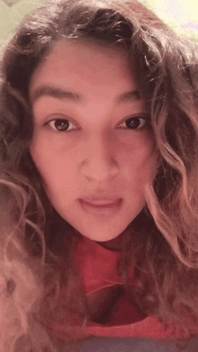 a close up of a woman 's face with a red top on