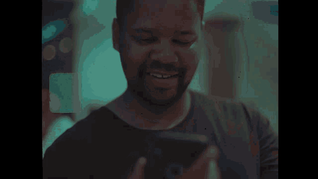 a man is smiling while looking at his phone
