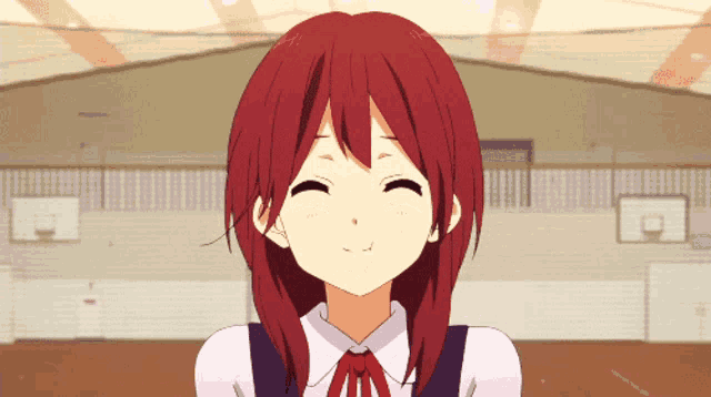 a girl with red hair is smiling with a basketball court in the background