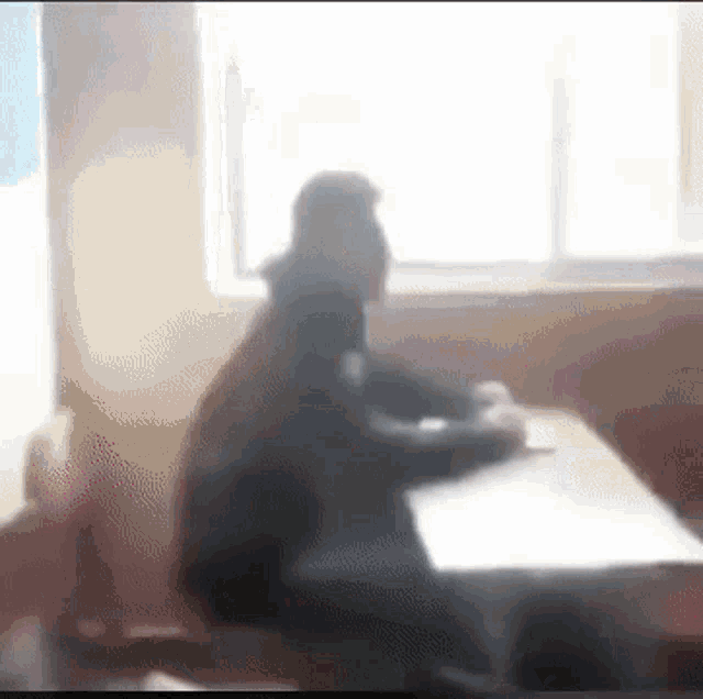 a man is sitting at a desk in a classroom .