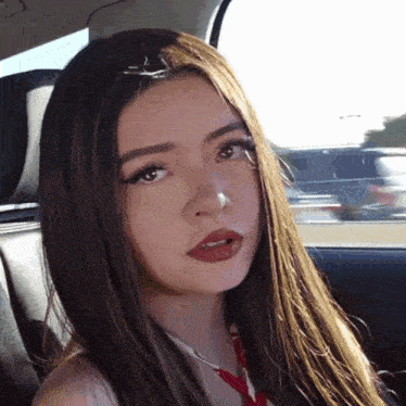 a woman with long hair is sitting in a car