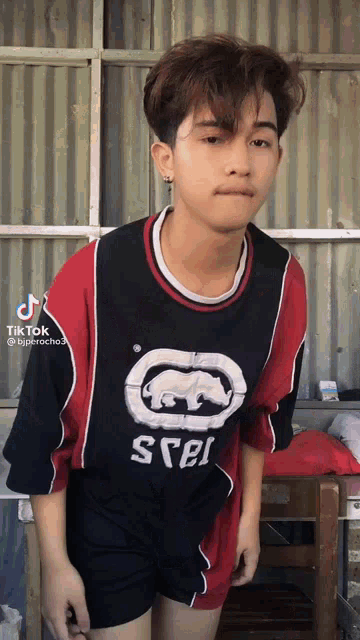 a young man wearing a red and black shirt that says ecko on it
