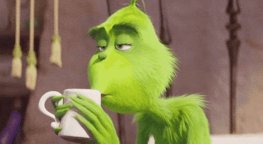 a green cartoon character is drinking a cup of coffee