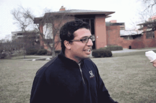 a man wearing glasses and a jacket that says ' university of michigan ' on it