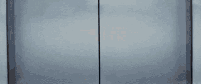 a woman in glasses is peeking out of a doorway