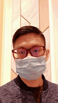 a man wearing glasses and a mask looks down at the camera