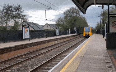 a yellow train is pulling into a station with a sign that says no smoking