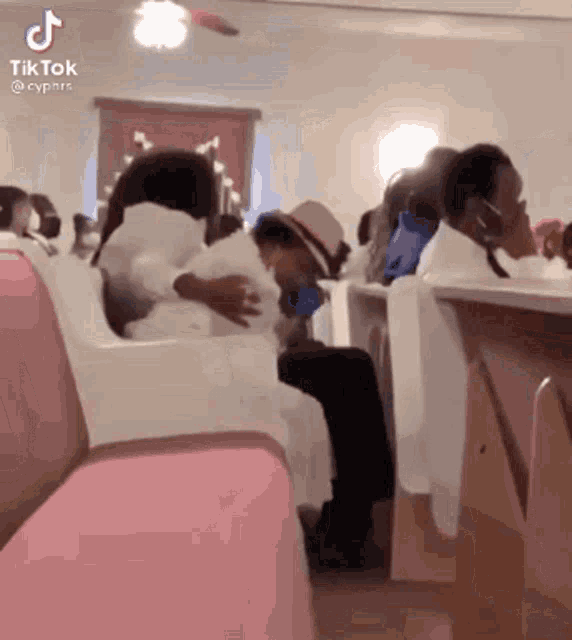 a group of people are sitting in a church and a woman is holding a child .