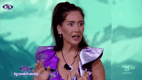 a woman in a purple dress is on a television screen with the words grandefratello on the bottom