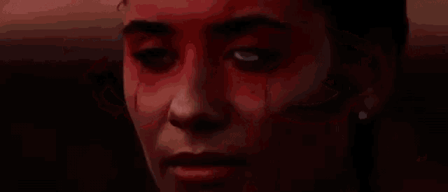 a close up of a person 's eyes with blood coming out of them and a glowing eye .