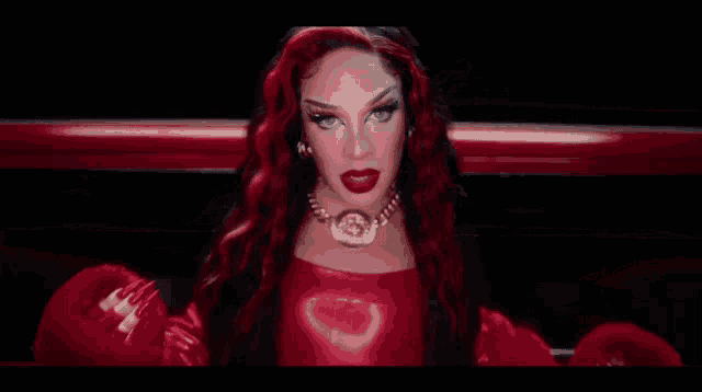 a woman with red hair and red lipstick is wearing a red dress