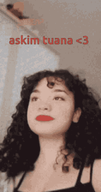 a woman with curly hair is looking up with the words askim tuana < 3 written above her