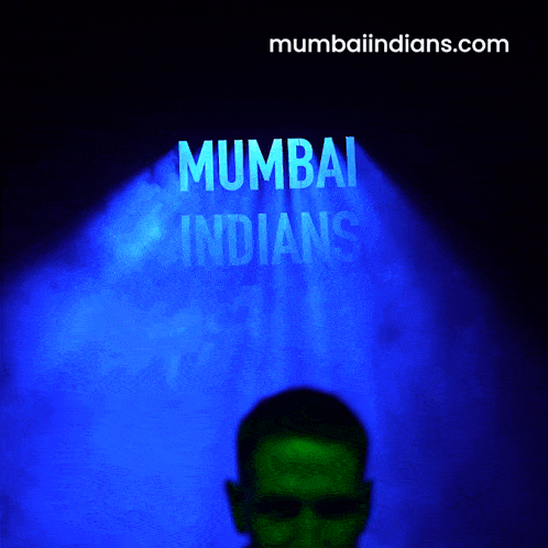 a man stands in front of a blue light that says ' mumbai indians ' on it