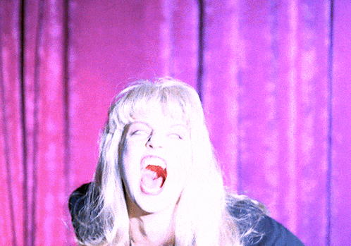 a woman with blonde hair is screaming with her mouth open