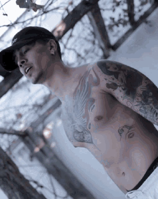 a shirtless man with tattoos on his chest and arms is wearing a black hat with the word abercrombie on it
