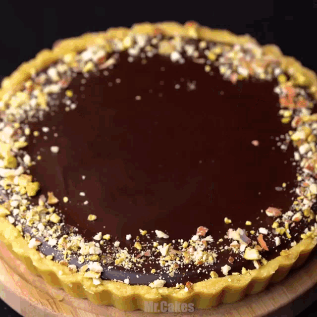 a chocolate tart is on a wooden cutting board with mr.cakes written in the corner