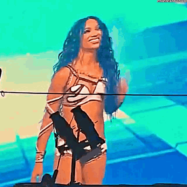 a woman in a bikini is standing on a stage in front of a microphone and smiling .