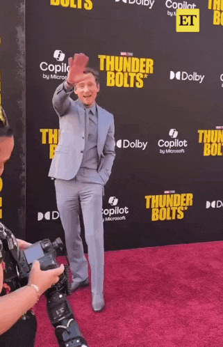 a man in a suit is standing on a red carpet with thunder bolts written on it