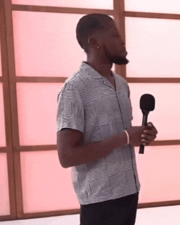 a man in a plaid shirt is holding a microphone in his hand .