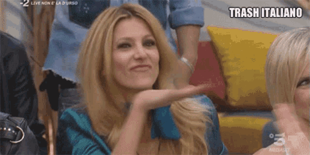 a woman in a blue shirt is making a gesture with her hands and says trash italiano