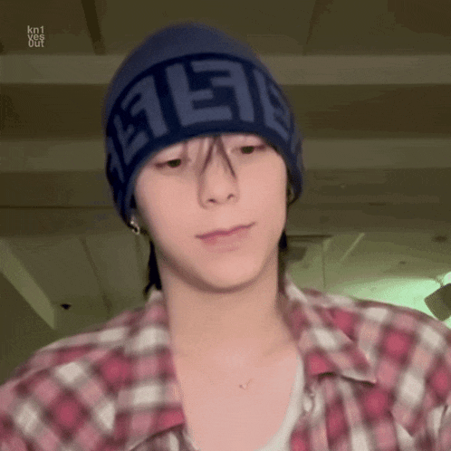 a young man wearing a plaid shirt and a blue hat .
