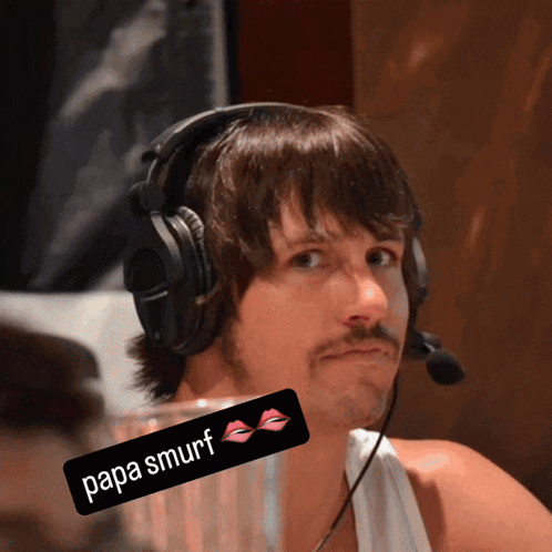a man wearing headphones and a microphone has a papa smurf sticker on his neck