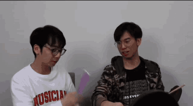 two men are sitting next to each other and one has a shirt that says musician on it