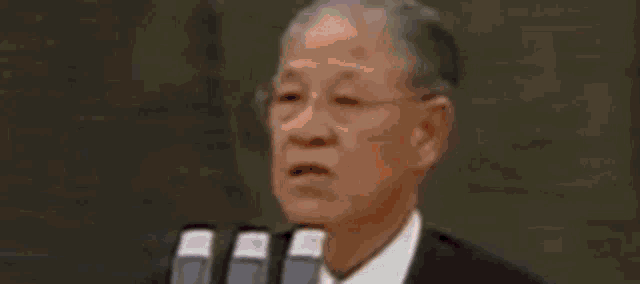 a man in a suit and white shirt is looking at the camera with his eyes closed .